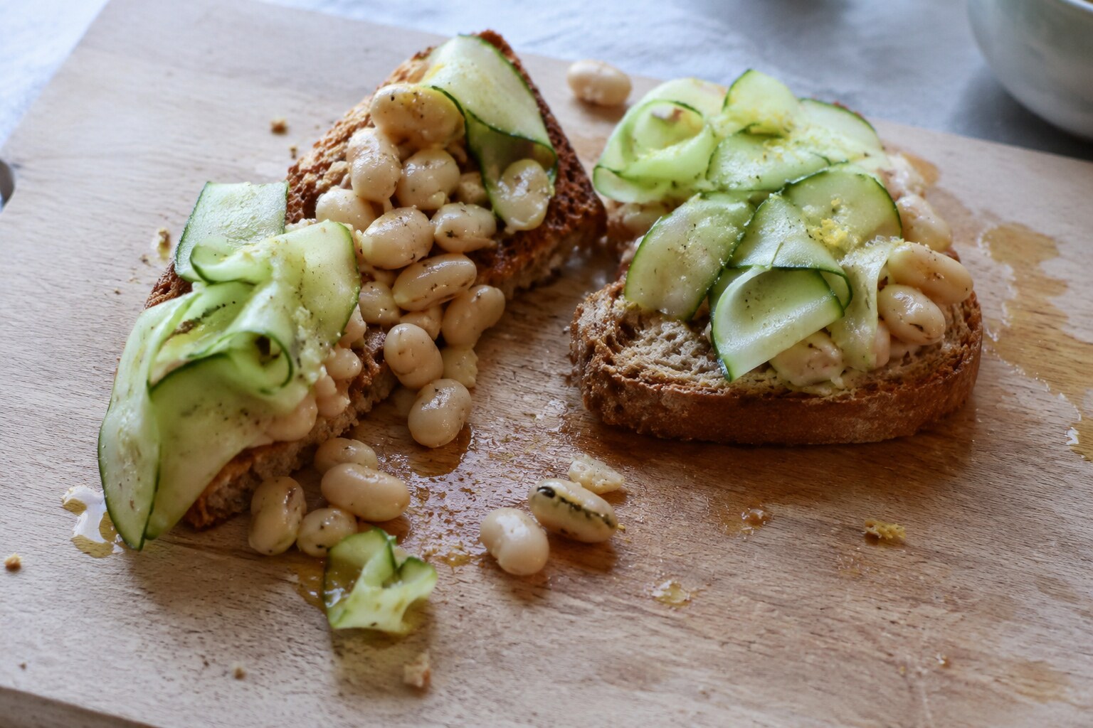 White bean toast tipped over with beans scattered on the board