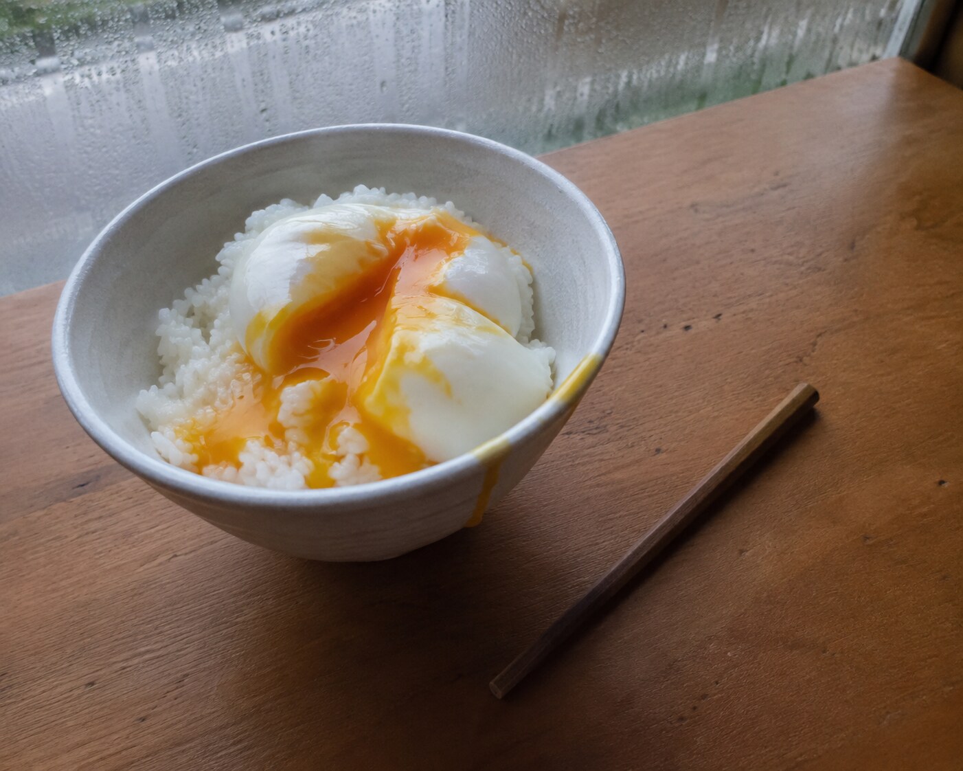 A jammy egg split over rice with yolk running into the bowl