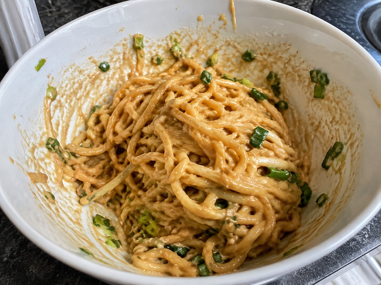 Miso noodles clumped in a bowl with sauce on the rim