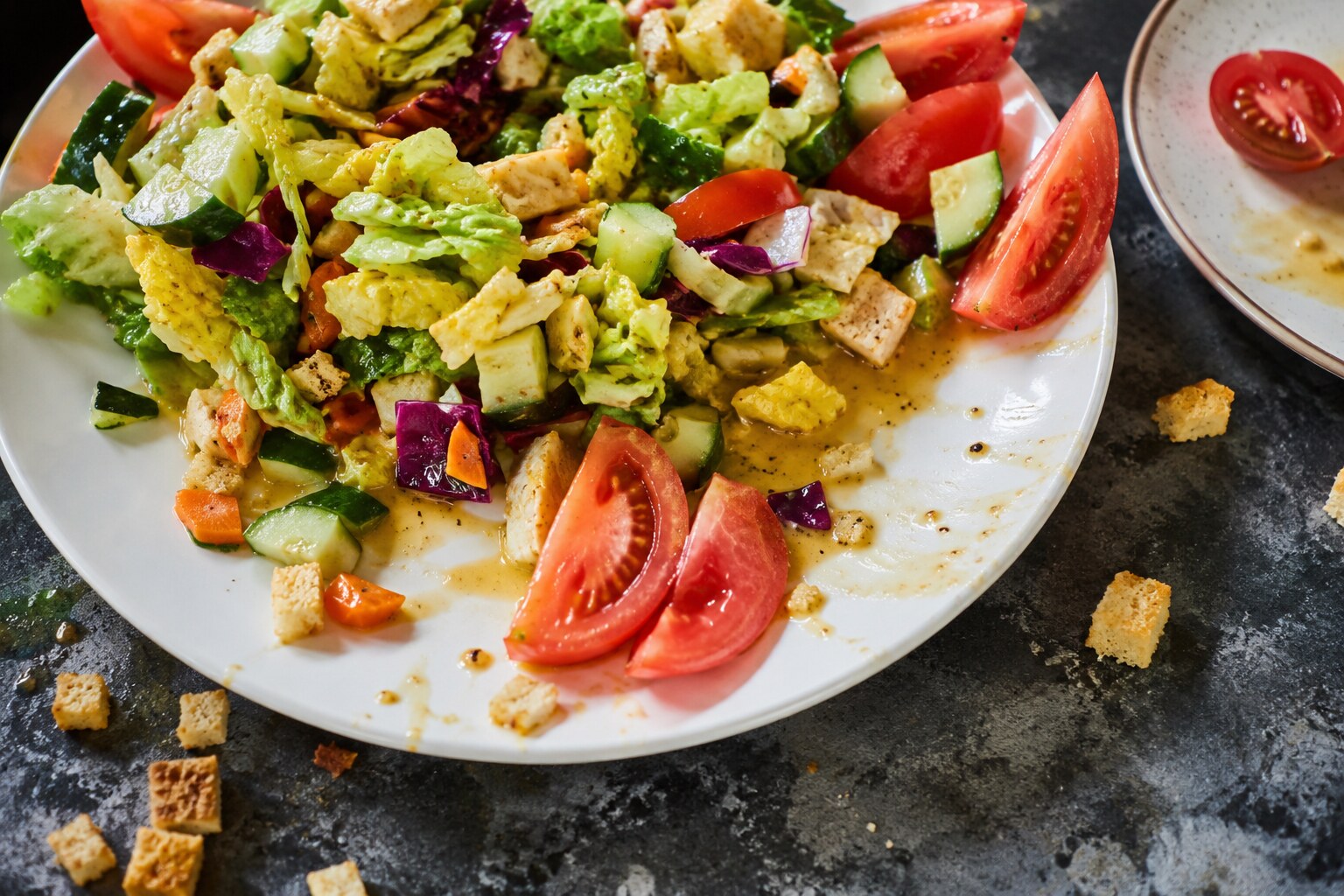 Chopped salad with dressing spilled and tomato wedges pushed aside
