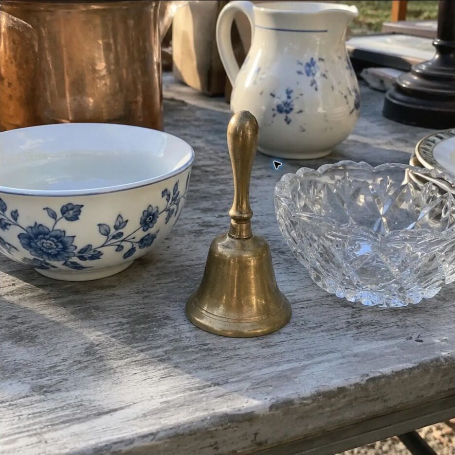 A small brass bell among blue-and-white dishes