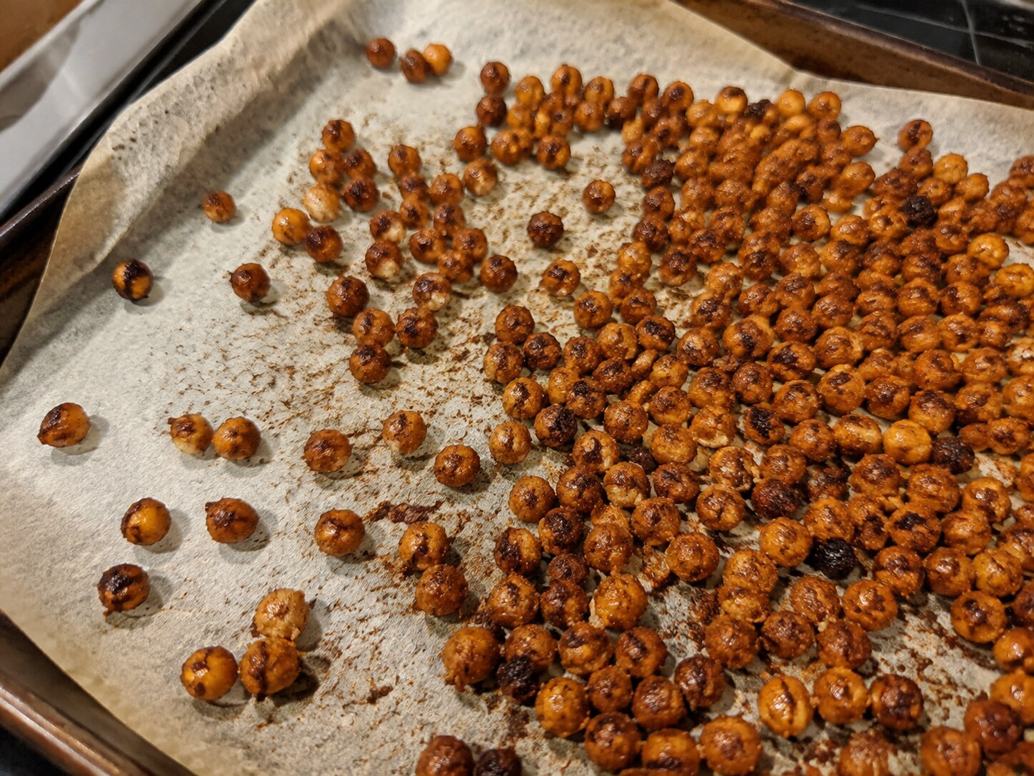 Smoky roasted chickpeas in a bowl beside a sheet pan
