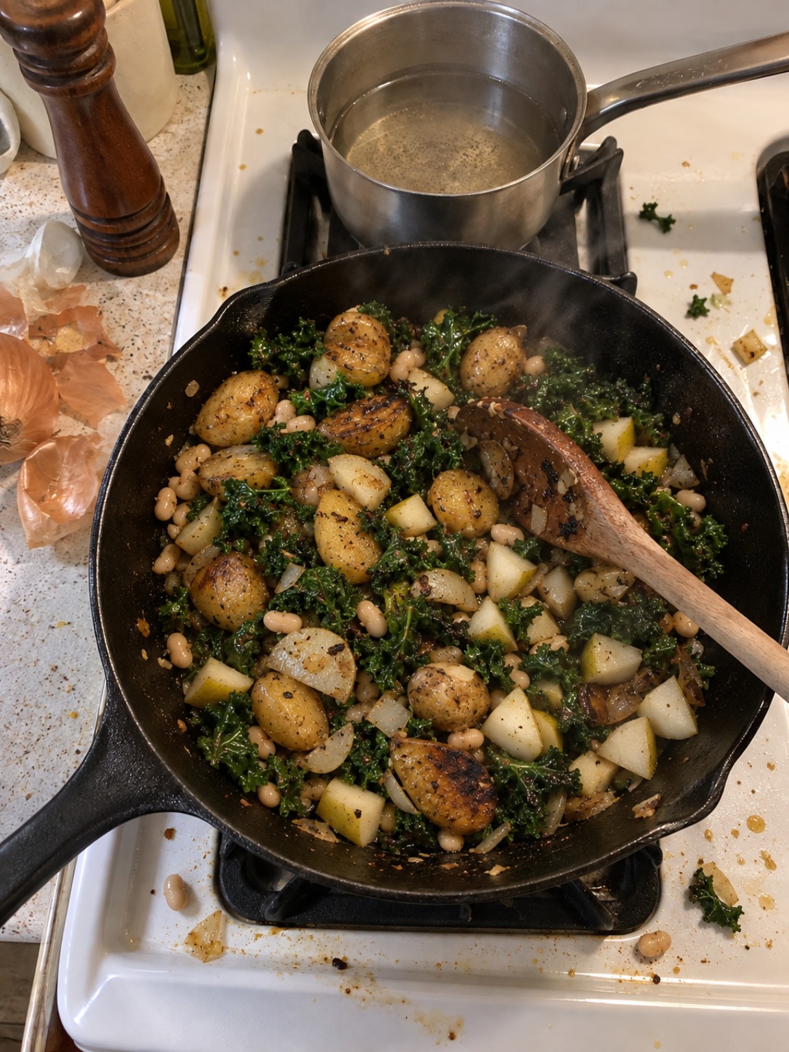 A finished skillet of potatoes, white beans, kale, onion, garlic, and pear